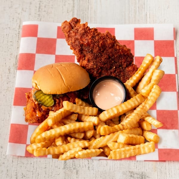 Spicy fried chicken sandwich with pickles, a large chicken tender, crinkle-cut fries, and dipping sauce.