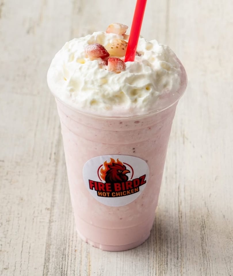 Strawberry milkshake with whipped cream, strawberry pieces, and a red straw, featuring the Fire Birdz logo.